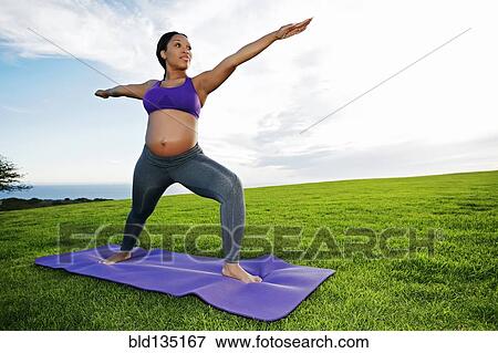 Stock Photo - Pregnant woman practicing yoga in park. Fotosearch