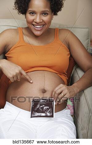 Pregnant woman showing sonogram by belly View Large Photo Image Stock Photo - Pregnant woman showing sonogram by belly. Fotosearch