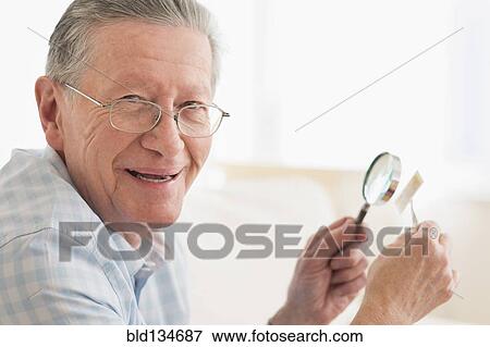 Senior Caucasian man examining stamp with magnifying glass View Large Photo Image Stock Photo - Senior Caucasian man examining stamp with magnifying glass. Fotosearch