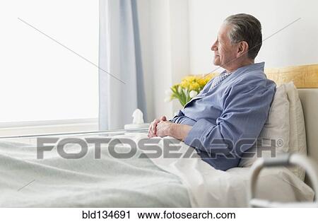 Stock Image - Senior Caucasian man sitting in hospital bed. Fotosearch