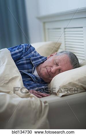Stock Image - Senior Caucasian man sleeping in bed. Fotosearch