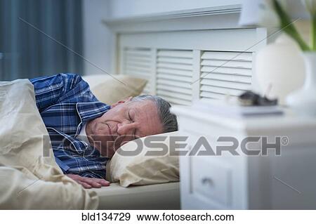 Stock Photo - Senior Caucasian man sleeping in bed. Fotosearch