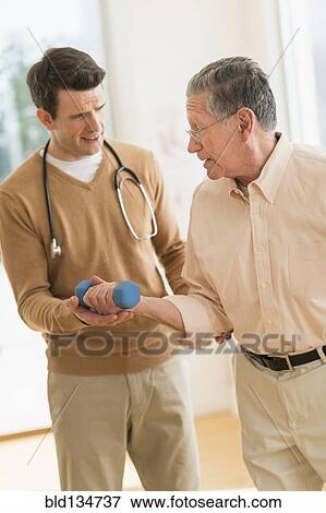 Stock Photo - Senior Caucasian man working with physical therapist. Fotosearch