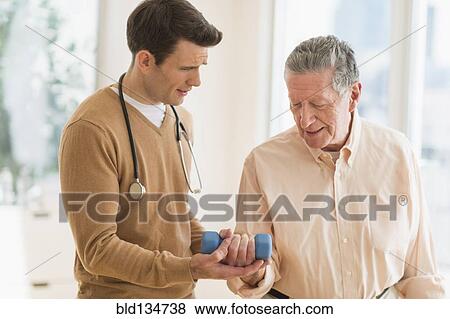 Stock Photo - Senior Caucasian man working with physical therapist. Fotosearch