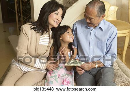 Senior couple giving granddaughter money View Large Photo Image Stock Photo - Senior couple giving granddaughter money. Fotosearch
