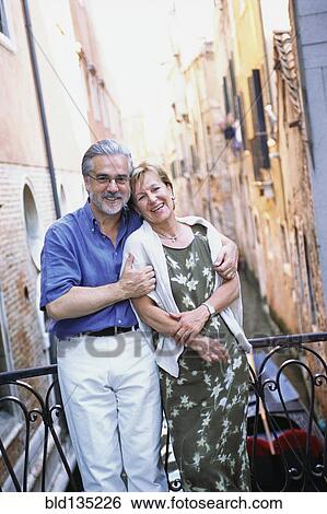 Stock Photograph - Senior couple hugging over urban canal, Venice, Veneto, Italy. Fotosearch