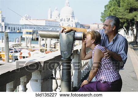 Stock Photo - Senior couple looking through telescope, Venice, Veneto, Italy. Fotosearch