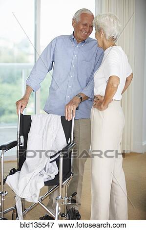 Senior couple standing by wheelchair View Large Photo Image Stock Photo - Senior couple standing by wheelchair. Fotosearch