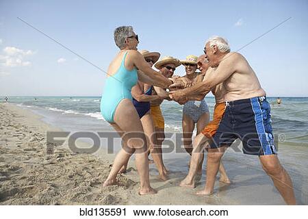 Senior friends cheering on beach View Large Photo Image Stock Image - Senior friends cheering on beach. Fotosearch