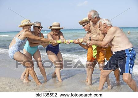 Senior friends playing tug-of-war on beach View Large Photo Image Stock Image - Senior friends playing tug-of-war on beach. Fotosearch