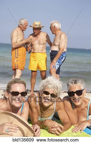 Senior friends relaxing on beach View Large Photo Image Stock Photo - Senior friends relaxing on beach. Fotosearch