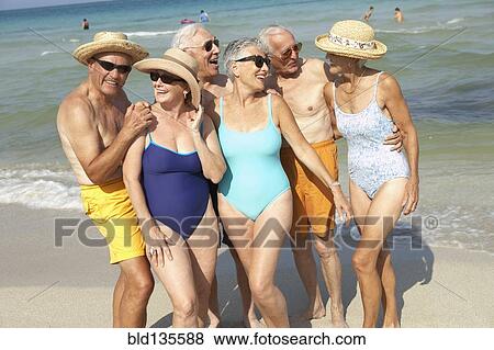 Stock Photo - Senior friends smiling on beach. Fotosearch