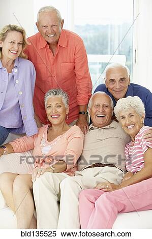Senior friends smiling together in living room View Large Photo Image Stock Photography - Senior friends smiling together in living room. Fotosearch