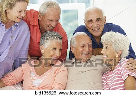 Stock Photograph - Senior friends talking in living room. Fotosearch