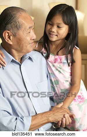 Stock Image - Senior man and granddaughter holding hands. Fotosearch