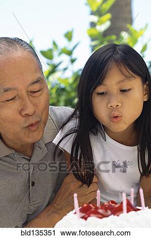 Stock Image - Senior man and granddaughter celebrating birthday. Fotosearch