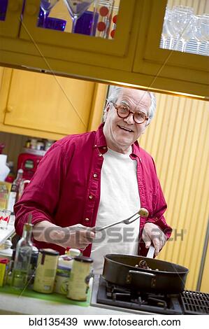 Senior man cooking in kitchen View Large Photo Image Stock Photo - Senior man cooking in kitchen. Fotosearch