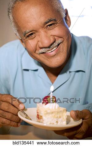 Stock Image - Senior man eating birthday cake. Fotosearch