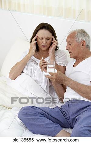 Senior man giving wife painkillers in bed View Large Photo Image Stock Photography - Senior man giving wife painkillers in bed. Fotosearch