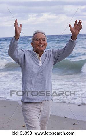 Stock Image - Senior man walking on beach. Fotosearch