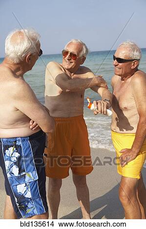 Senior men applying sunscreen on beach View Large Photo Image Picture - Senior men applying sunscreen on beach. Fotosearch
