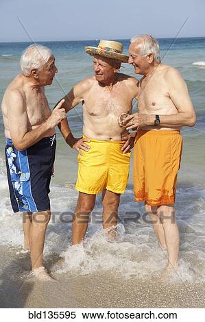 Stock Photography - Senior men talking on beach. Fotosearch