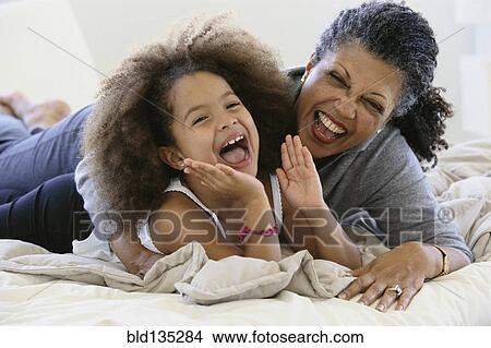Senior woman and granddaughter laughing on bed View Large Photo Image Picture - Senior woman and granddaughter laughing on bed. Fotosearch