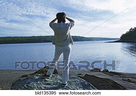 Stock Photography - Senior woman overlooking rural lake. Fotosearch