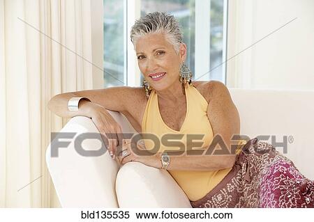 Stock Photography - Senior woman sitting on sofa. Fotosearch