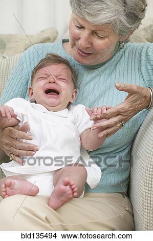Senior woman with crying granddaughter on sofa View Large Photo Image Picture - Senior woman with crying granddaughter on sofa. Fotosearch
