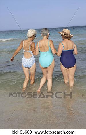 Senior women walking in waves on beach View Large Photo Image Stock Image - Senior women walking in waves on beach. Fotosearch