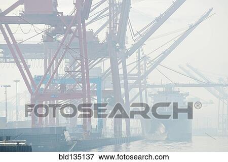 Shipping cranes in foggy industrial harbor View Large Photo Image Stock Photo - Shipping cranes in foggy industrial harbor. Fotosearch