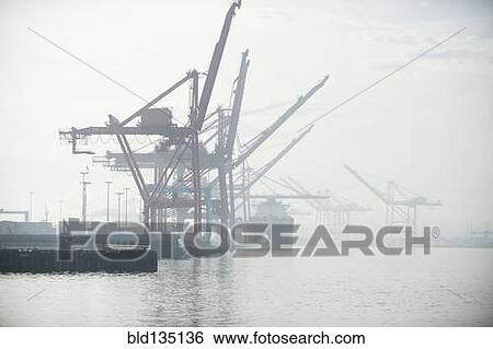 Shipping cranes in foggy industrial harbor View Large Photo Image Stock Photograph - Shipping cranes in foggy industrial harbor. Fotosearch