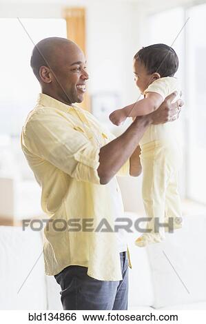 Stock Photograph - Smiling father holding baby. Fotosearch