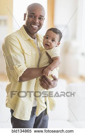 Smiling father holding baby View Large Photo Image Stock Photography - Smiling father holding baby. Fotosearch