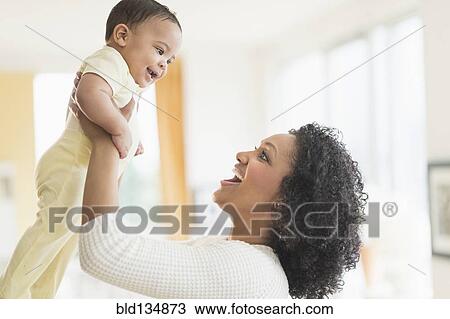 Stock Image - Smiling mother playing with baby. Fotosearch