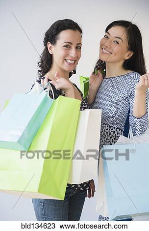 Stock Image - Smiling women shopping together. Fotosearch