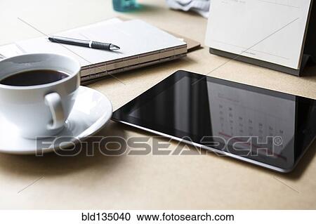 Stock Image - Tablet computer on table with book and coffee. Fotosearch