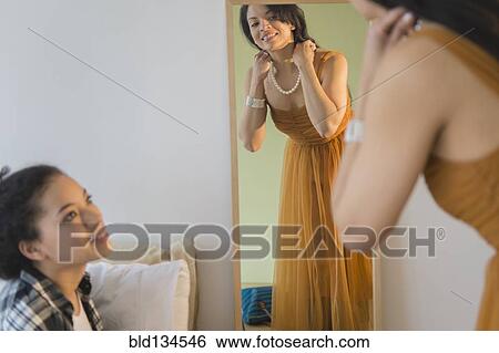 Teenage girl watching mother put on evening gown View Large Photo Image Stock Photograph - Teenage girl watching mother put on evening gown. Fotosearch