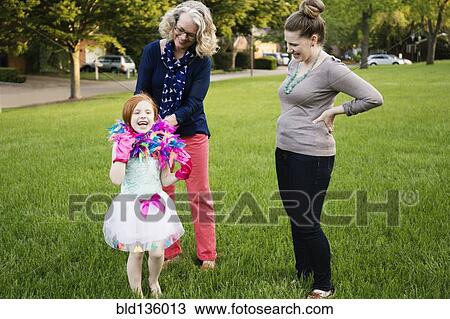 Stock Image - Three generations of Caucasian women standing in park. Fotosearch