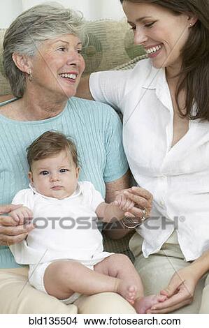 Picture - Three generations of family sitting on sofa. Fotosearch