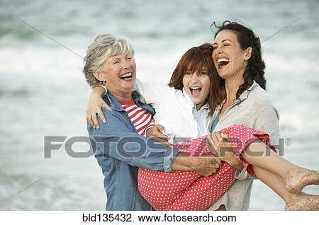 Stock Image - Three generations of women playing on beach. Fotosearch