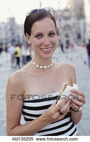 Woman eating sandwich on city street View Large Photo Image Stock Photography - Woman eating sandwich on city street. Fotosearch