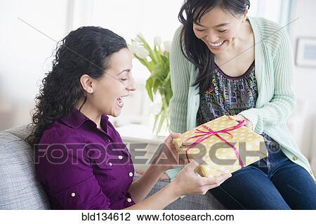 Stock Image - Woman giving friend birthday present. Fotosearch
