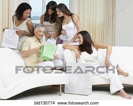 Woman opening presents with friends on sofa View Large Photo Image Picture - Woman opening presents with friends on sofa. Fotosearch