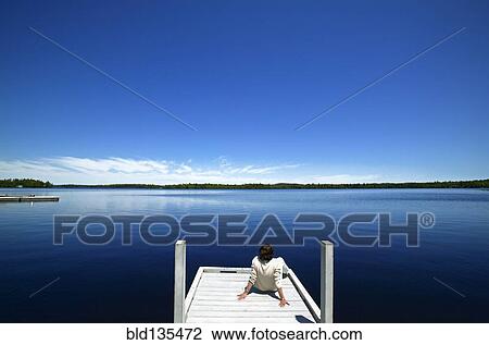 Woman overlooking lake on wooden dock View Large Photo Image Stock Image - Woman overlooking lake on wooden dock. Fotosearch