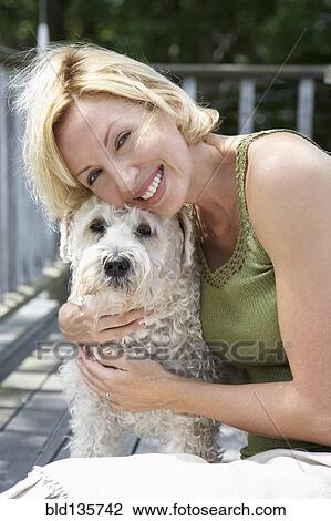 Woman petting dog on wooden patio View Large Photo Image Stock Image - Woman petting dog on wooden patio. Fotosearch