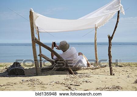 Woman relaxing under homemade shade on beach View Large Photo Image Stock Photo - Woman relaxing under homemade shade on beach. Fotosearch