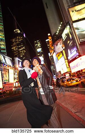 Stock Photography - Woman smiling on city street lit up at night. Fotosearch