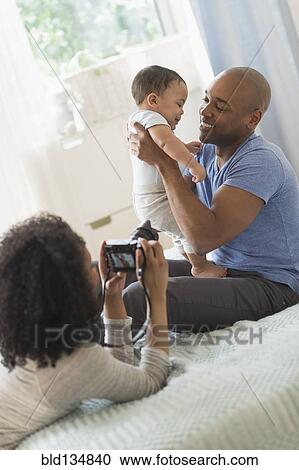 Woman taking picture of father and baby View Large Photo Image Stock Image - Woman taking picture of father and baby. Fotosearch